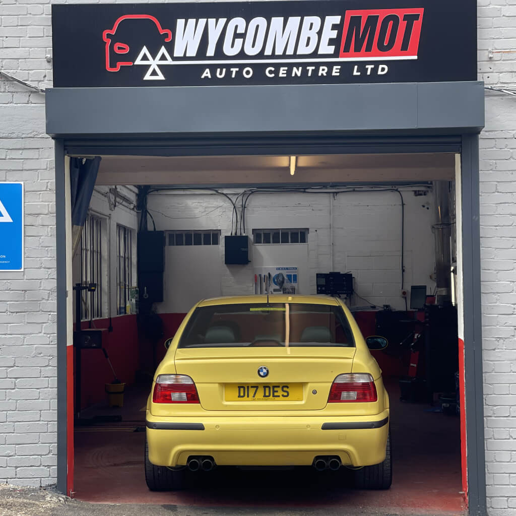 A Yellow car on a ramp inside the workshop